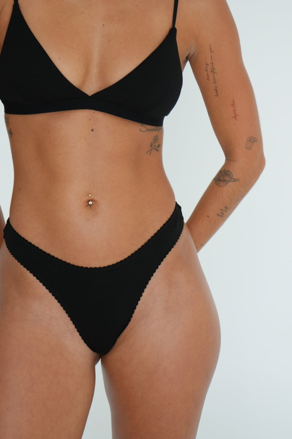 Model wearing Women’s natural fibre thong g-string bamboo black with flattering high leg cut and picot trim elastic on white background