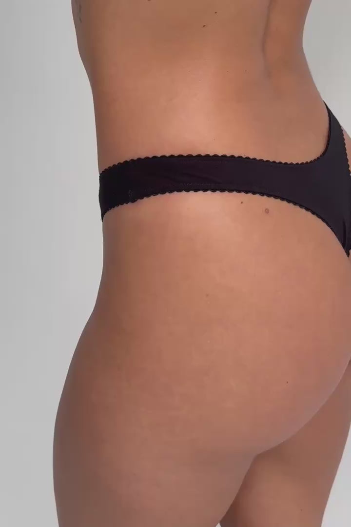 Video of model wearing Women’s natural fibre thong g-string bamboo black with print high leg cut and picot trim elastic on white background